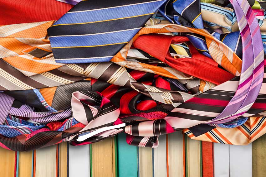 עניבות ססגוניות ושורת ספרי וינטג' בכריכות צבעוניות מדגימות עריכה ספרותית מפרשת, המקשרת בין הפרטים לבין הסיפור.